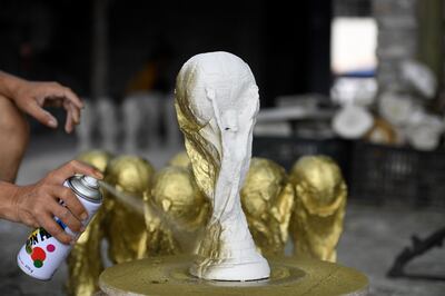This picture taken on June 5, 2018 shows Vietnamese craftsman Vuong Hong Nhat spraying gold colour paint on a plaster model of the football World Cup trophy at a workshop in Hanoi. Demand in football-mad Vietnam is soaring for the hand made plaster models of the real 18-carat gold trophy that will go to the winners of the month-long World Cup hosted by Russia that starts on June 14.  - TO GO WITH Fbl-lifestyle-WC-2018-Vietnam by Quy Le BUI
 / AFP / Nhac NGUYEN / TO GO WITH Fbl-lifestyle-WC-2018-Vietnam by Quy Le BUI
