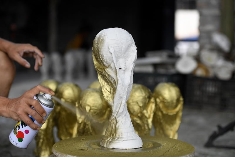This picture taken on June 5, 2018 shows Vietnamese craftsman Vuong Hong Nhat spraying gold colour paint on a plaster model of the football World Cup trophy at a workshop in Hanoi. Demand in football-mad Vietnam is soaring for the hand made plaster models of the real 18-carat gold trophy that will go to the winners of the month-long World Cup hosted by Russia that starts on June 14.  - TO GO WITH Fbl-lifestyle-WC-2018-Vietnam by Quy Le BUI
 / AFP / Nhac NGUYEN / TO GO WITH Fbl-lifestyle-WC-2018-Vietnam by Quy Le BUI
