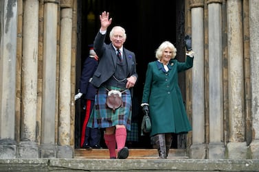 Britain's King Charles III, wearing a kilt, and Britain's Camilla, Queen Consort wave as they walk to meet members of the public after leaving from Dunfermline Abbey in Dunfermline in south east Scotland on October 3, 2022.  (Photo by Andrew Milligan  /  POOL  /  AFP)