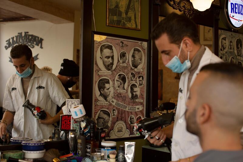 A barber gives a customer a haircut after coronavirus restrictions were eased, opening shopping centers, gyms, barber shops, among other sites in Jerusalem, Tuesday, Feb. 23, 2021. (AP Photo/Maya Alleruzzo)