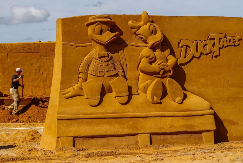 A sand carver works on a Ducktales sculpture. Yves Herman / Reuters