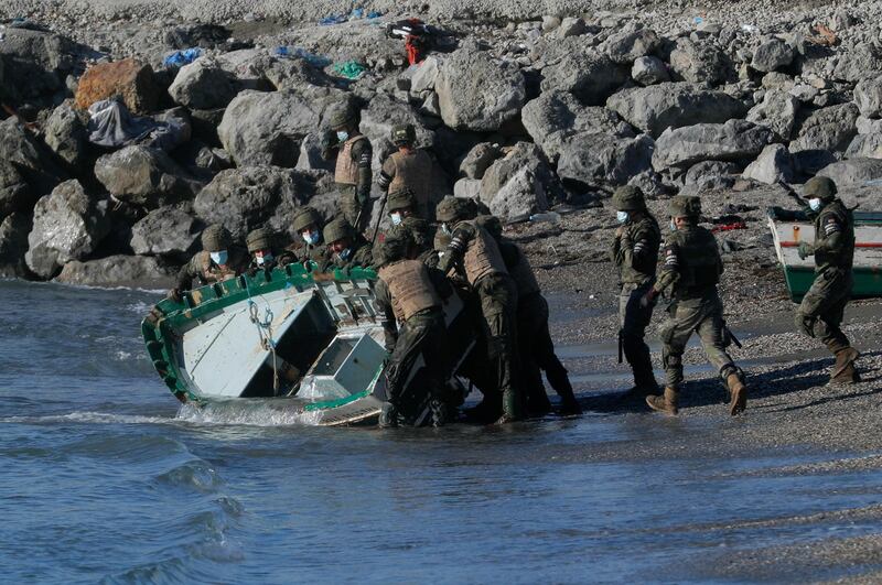 Spanish soldiers remove the water from a boat used by Moroccan migrants at El Tarajal beach, near the fence between the Spanish-Moroccan border. Reuters