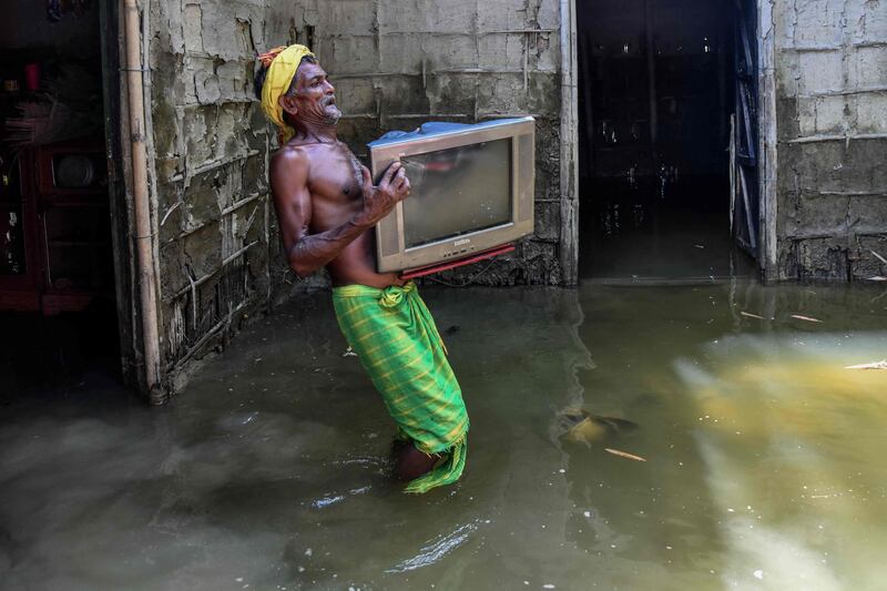 A man carries his belongings from his partially submerged house in India's Assam state. AFP