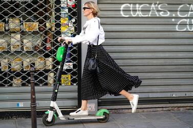 PARIS, FRANCE - JULY 03: A woman wears a white shirt, sunglasses, a black and white polka dots skirt, a black bag, white sneakers, and is riding electric a scooter Lime-S from the bike sharing service company "Lime", outside Valentino, during Paris Fashion Week -Haute Couture Fall/Winter 2019/2020, on July 03, 2019 in Paris, France. (Photo by Edward Berthelot/Getty Images)