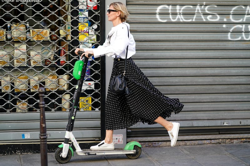 PARIS, FRANCE - JULY 03: A guest wears a white shirt, sunglasses, a black and white polka dots skirt, a black bag, white sneakers, and is riding electric a scooter Lime-S from the bike sharing service company "Lime", outside Valentino, during Paris Fashion Week -Haute Couture Fall/Winter 2019/2020, on July 03, 2019 in Paris, France. (Photo by Edward Berthelot/Getty Images)