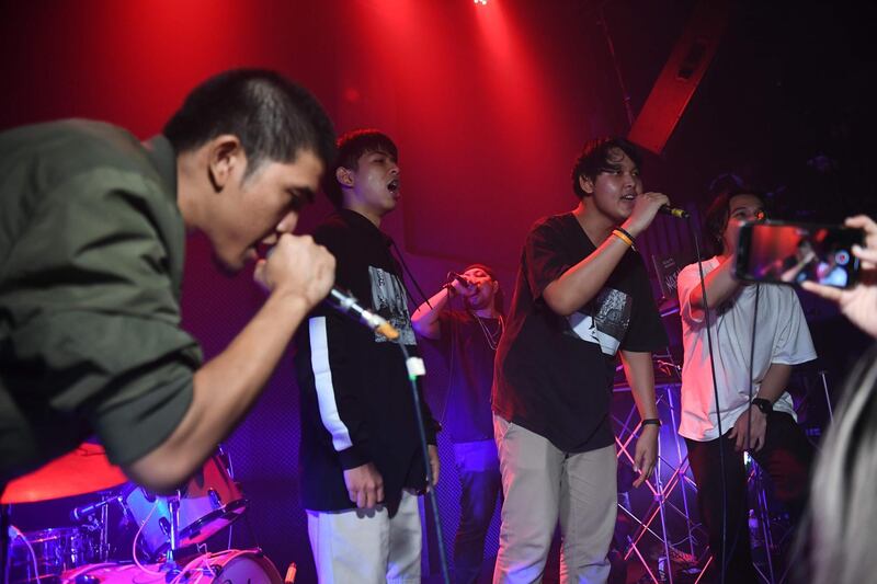 An audience member (2nd-R) raps with members of the group Rap Against Dictatorship on stage in Bangkok on October 27, 2018. A group of Thai rappers has touched a nerve with an impassioned and now-viral music video lobbing fiery rhymes at the ruling junta, as police mull filing charges against the lyricists. The song "Prathet Ku Mee" (Which is My Country), uploaded to YouTube on October 22, has racked up more than 6.4 million views and tens of thousands of comments since it went live on the platform, prompting authorities to take notice. / AFP / Lillian SUWANRUMPHA
