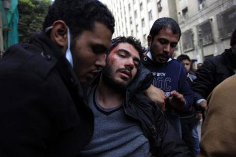 A injured man is evacuated during clashes near Tahrir Square in Cairo on Friday. Khalil Hamra / AP Photo