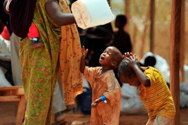 A newly arrived Somali refugee washes her children on August 14, 2011 immediately after they were registered and received rations at the Dadaab refugee complex in Dadaab. UN Under-Secretary-General for Humanitarian Affairs and Emergency Relief Coordinator Valerie Amos toured today the refuge complex holding more that 440,000 refugees during the third day of her visit to southern Somalia and to the Kenya-hosted refugee complex to asses the impact of the famine.Her visit comes as the UN said it’s moving on two fronts to counter the worsening food crisis in the Horn of Africa, with an immediate infusion of food in an area where 640,000 children alone are threatened with acute malnutrition. AFP PHOTO/Tony KARUMBA
 *** Local Caption ***  611151-01-08.jpg