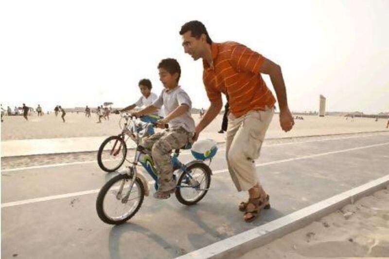 Marcus Abdelsayed teaches his son Anthony how to ride while his brother Peter follows in the background at Jumeirah Open Beach.