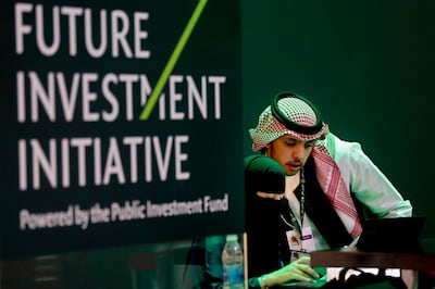FILE - In this Oct. 22, 2018, file photo, Saudi employees print badges of participants of the Future Investment Initiative in Riyadh, Saudi Arabia. Lured by a long-looming stock offering of Saudi Arabia's massive state-run oil company, investors and business leaders have returned to the kingdom's capital for an investment forum overshadowed last year by the assassination of Washington Post columnist Jamal Khashoggi. (AP Photo/Amr Nabil, File)