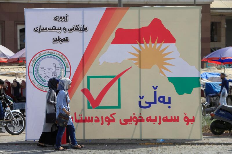 Iraqi women walk on the street, near banners supporting the referendum for independence for Kurdistan in Erbil, Iraq September 21, 2017. REUTERS/Alaa Al-Marjani