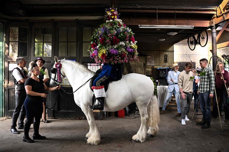 John Turner, the 'King' of Castleton Garland Day, on horse-back, covered to the waist in a heavy, bell-shaped floral Garland, prepares to parade through the village of Castleton in the Peak District, northern England on May 29, 2023.  The date of the custom coincides with Oak Apple Day and it is said to commemorate the restoration of King Charles II in 1660.  The Garland is meant to represent the oak tree in which he hid after the Battle of Worcester.  (Photo by Oli SCARFF  /  AFP)