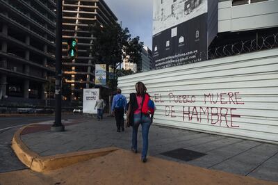 Pedestrians walk past graffiti that reads "The People Are Dying Of Hunger" in Caracas, Venezuela, on Wednesday, Sept. 12, 2018. As the Venezuelan diaspora earns ever greater income, they're sending more to struggling relatives back home. Remittances surged to $1.5 billion in 2017 and will climb a further 60 percent this year to $2.4 billion, according to Caracas-based consultancy Ecoanalitica. Photographer: Adriana Loureiro Fernandez/Bloomberg