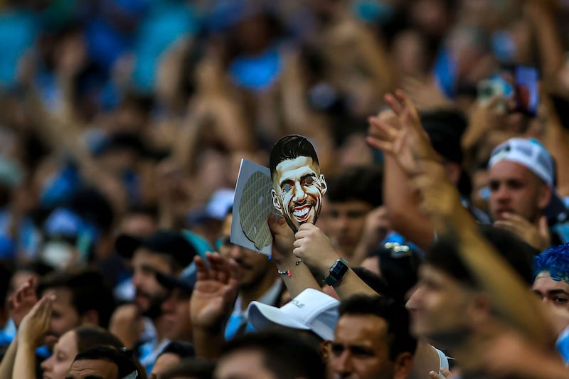 A Gremio holds up a mask of Luis Suarez during the game against Vasco da Gama. AFP