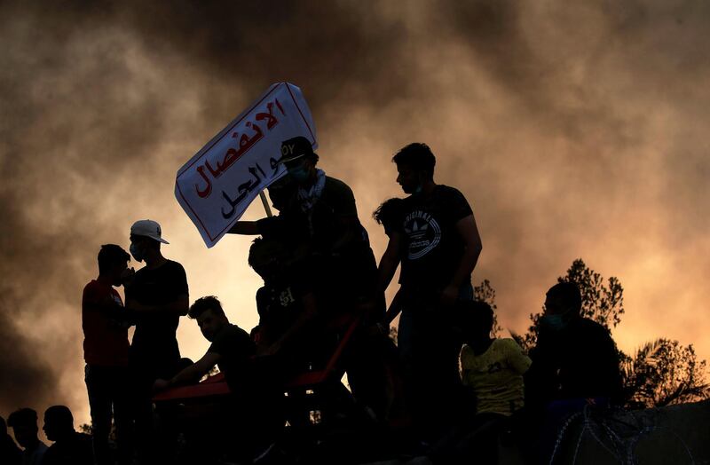 Protesters stand on concrete blast walls during anti government protest near the building of the government office in Basra, Iraq. Reuters