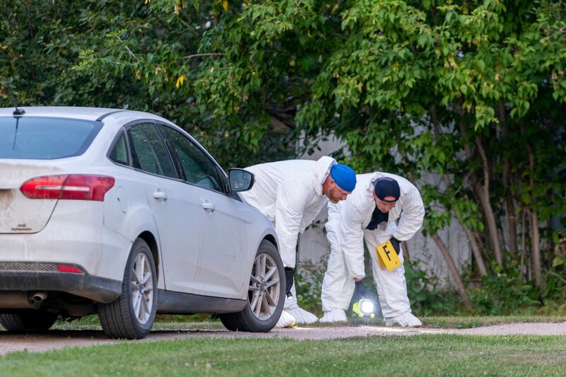 Investigators examine the ground as they search for clues at the scene of a stabbing in Weldon. AP