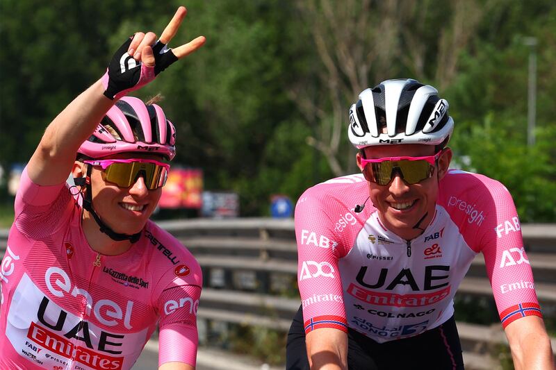 Team UAE's Slovenian rider Tadej Pogacar wearing the overall leader's pink jersey gives a victory sign as he rides alongside teammate Vegard Laengen. AFP