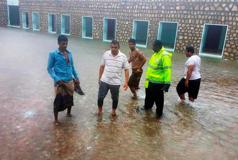 Men stand in floodwater in Hadibu, Socotra.