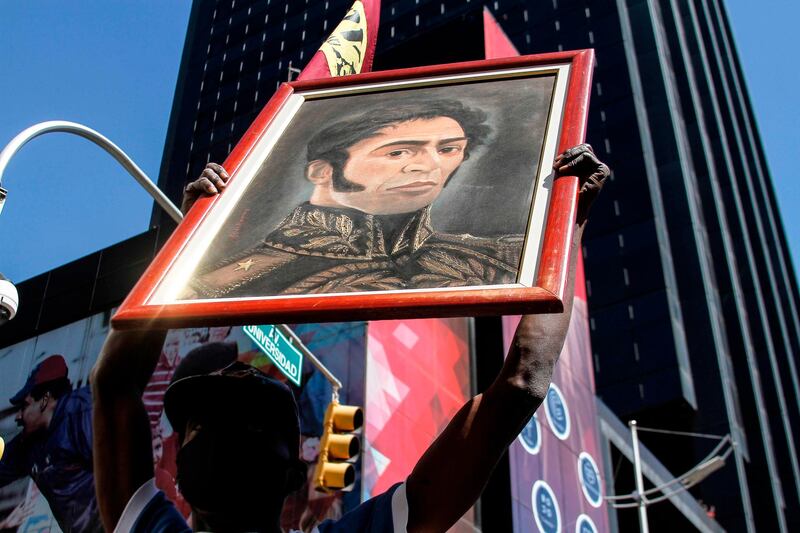 A supporter of the Venezuelan government holds a portrait depicting Venezuelan liberator Simon Bolivar outside the National Assembly during an extraordinary session, in Caracas. AFP
