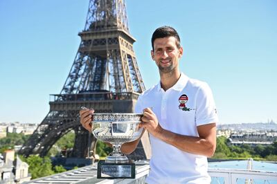 TOPSHOT - Serbia's Novak Djokovic poses with the trophy in front of the Eiffel tower, on June 14, 2021 in Paris, during a photocall one day after winning  the Roland Garros 2021 French Open tennis tournament. / AFP / POOL / Christophe ARCHAMBAULT
