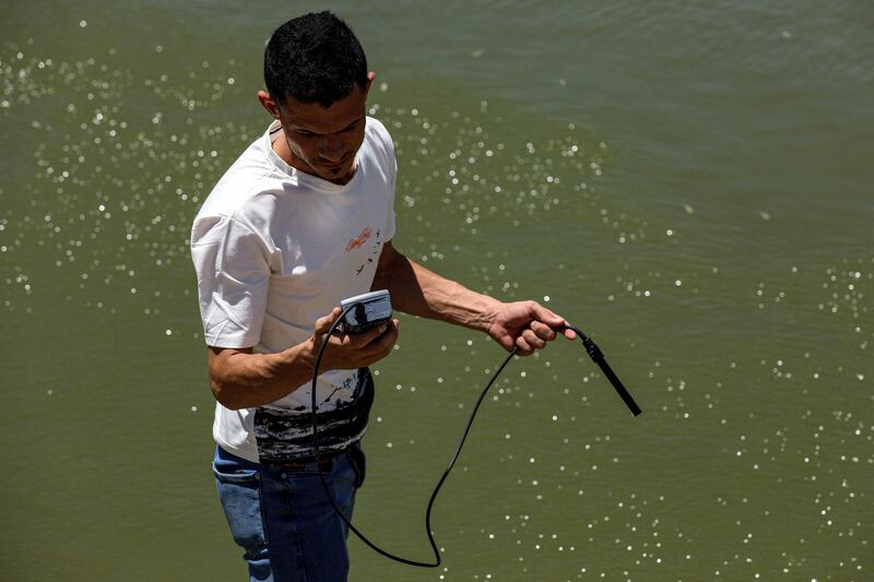 An employee of Iraq's Ministry of Water Resources measures the oxygen level and salinity of the water of the Amshan river, which is fed by the Tigris. AFP