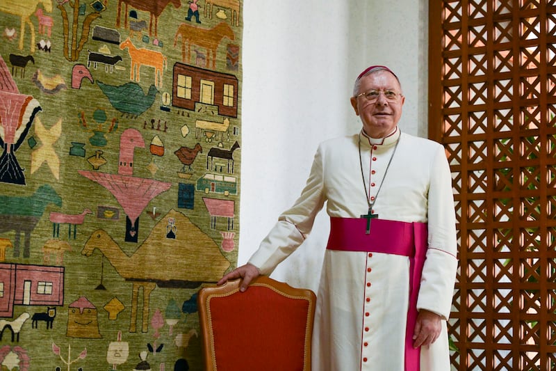 Bishop Hinder stands beside a handwoven carpet at his residence in Abu Dhabi.
