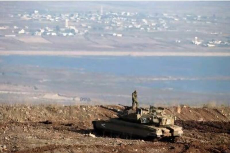 An Israeli soldier stands on a Merkava tank in the Golan Heights, overlooking the Syrian village of Breqa.