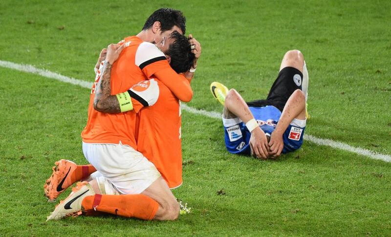 Dominik Stroh — Engel (L) and Benjamin Gorka (C) of Darmstadt celebrate while a Bielefeld player looks dejected after the Second Bundesliga Playoff Second Leg match between Armenia Bielefeld and Darmstadt 98 at Schueco Arena in Bielefeld, Germany. Thomas Starke / Getty Images