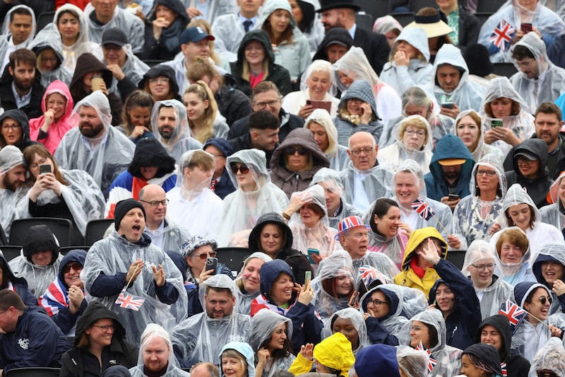 People awaiting the coronation procession to begin shelter from the rain in London. Reuters