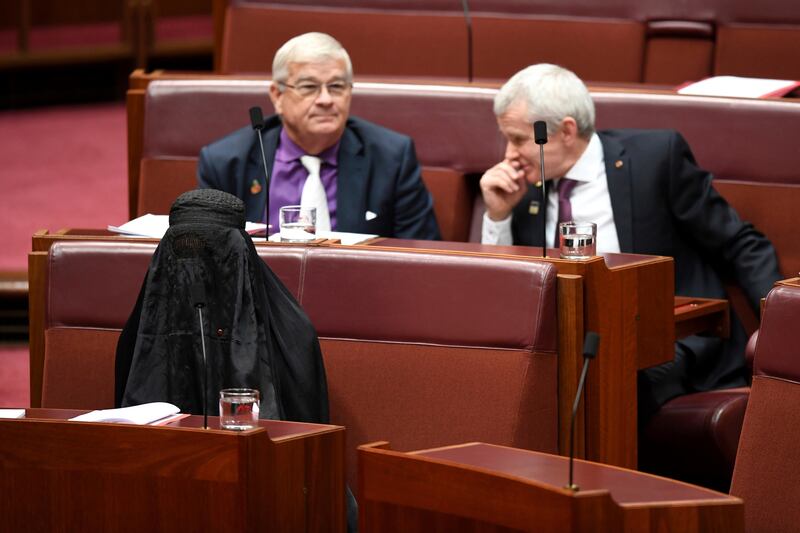 Sen. Pauline Hanson, bottom left, wears a burqa during question time in the Senate chamber at Parliament House in Canberra, Australia, Thursday, Aug. 17, 2017. Hanson, leader of the anti-Muslim, anti-immigration One Nation minor party, sat wearing the black head-to-ankle garment for more than 10 minutes before taking it off as she rose to explain that she wanted such outfits banned on national security grounds. (Lukas Coch/AAP Image via AP)