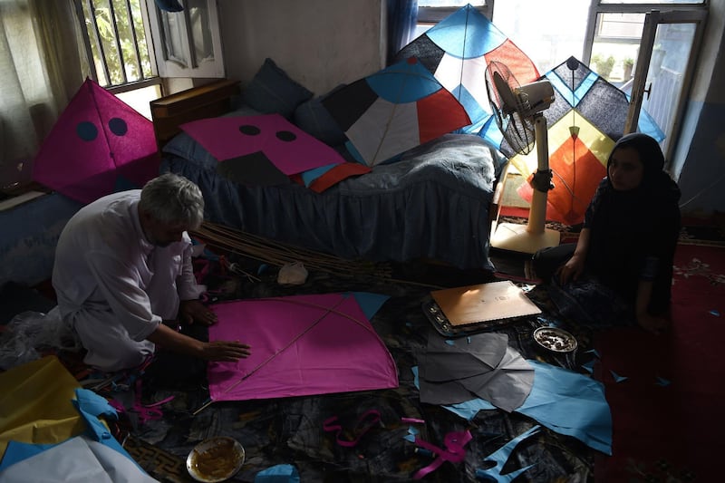 Kite vendor Halim Muhammadi cuts tissue papers as he makes kites with his daughter Nigina in their home in Kabul.
