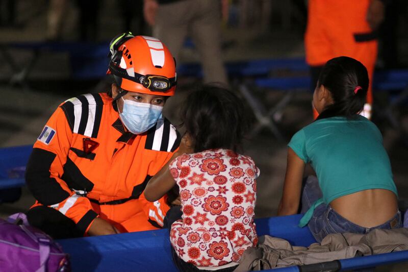 Handout picture released by Bomberos Volutarios shows Firefighters help evacuees settle in a temporary shelter in Santa Lucia Cotzumalguapa south Guatemala City on March 7, 2022.  - Some 370 people from a community based at the base of the Fuego volcano, in southwestern Guatemala, were evacuated on Monday following the increase in the volcanic activity of the colossus, the Civil Protection Agency reported.  AFP