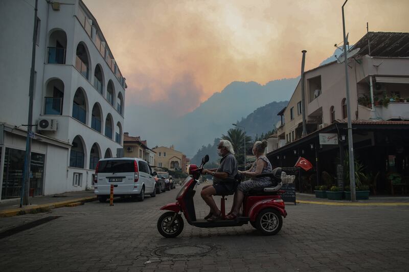 People use a scooter in Turunc before the village is evacuated.