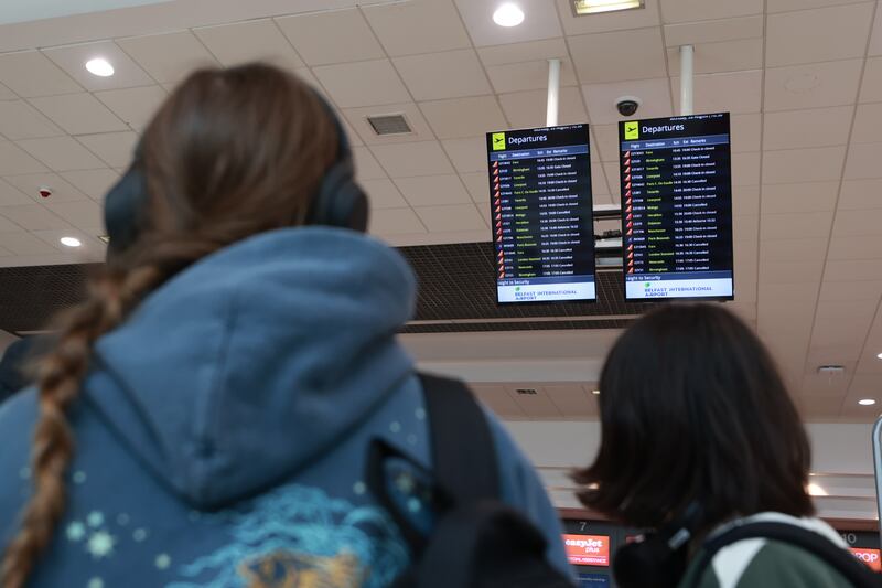 Passengers look at departure boards at Belfast International Airport. PA