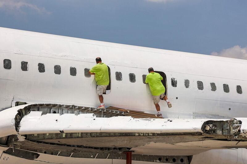 Atallah and Khamis Al Sairafi climb into the fuselage of the Boeing 707. Electricians and painters are working on the aircraft, which will become a restaurant and events hall.