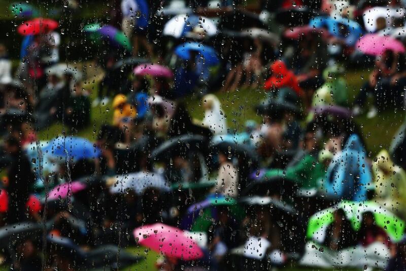 A view of raindrops on a window with fans shelteriing under umbrellas in the background as rain delays play on Day 7 of the 2014 Wimbledon Championships on Monday at the All England Club in London, England. Dan Kitwood / Getty Images