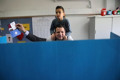 Ayman Odeh, leader of Hadash-Ta'al party, holds up his ballot paper as he stands behind a voting booth and carries his son on his shoulders as Israelis began voting in a parliamentary election, at a polling station in Haifa, Israel April 9, 2019. REUTERS/Ammar Awad