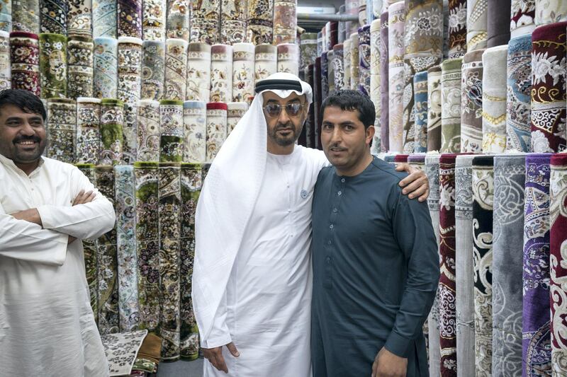 ABU DHABI, UNITED ARAB EMIRATES -  February 22, 2018: HH Sheikh Mohamed bin Zayed Al Nahyan, Crown Prince of Abu Dhabi and Deputy Supreme Commander of the UAE Armed Forces (center L), stands for a photograph with staff at Al Safa Carpet shop, in the carpet market of the Mina Zayed Port. 
( Ryan Carter for the Crown Prince Court - Abu Dhabi )
---