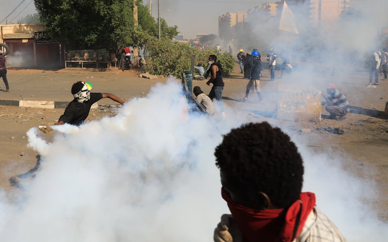 Sudanese protesters take cover as security forces fire tear gas during clashes with security forces at an anti-coup protest, in Khartoum, Sudan, 09 January 2022.  Security forces fired tear gas to disperse protesters gathering in Khartoum and attempting to march towards the presidential palace, as part of the continuing protesting movement against a military coup in October 2021.  The protest was organized a day after the UN envoy for Sudan said the international group will invite different parties for talks in Sudan to end the crisis. EPA