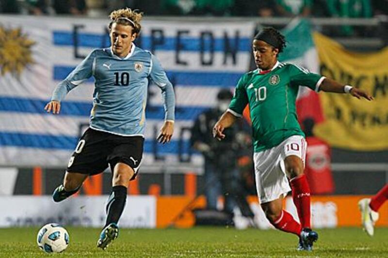 Diego Forlan, left, is put under pressure by Mexico's Giovani Dos Santos during Uruguay's 2-0 win to set up their quarter-final with Argentina at the Copa America.