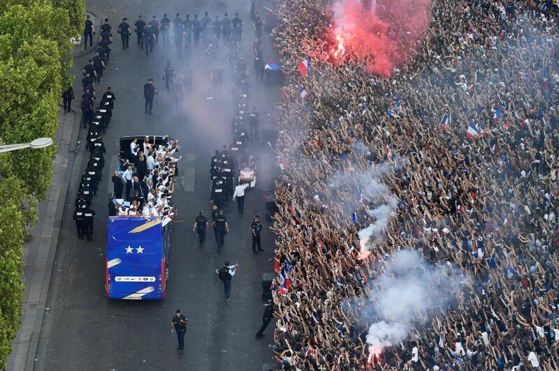 France's fans greet France's national football team players as they celebrate on the roof of a bus while they parade down the Champs-Elysee avenue in Paris, on July 16, 2018 after winning the Russia 2018 World Cup final football match. / AFP / Bertrand GUAY
