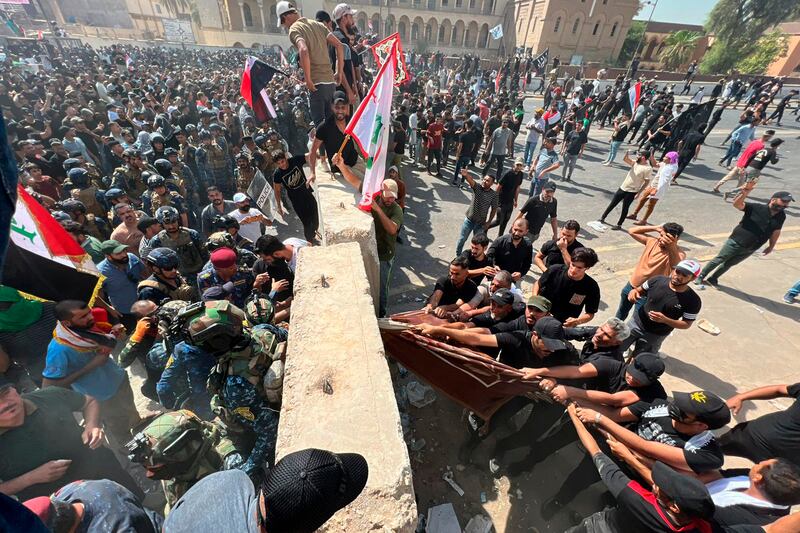 Protesters try to remove concrete barriers, to cross the bridge towards the Green Zone in Baghdad. AP Photo 