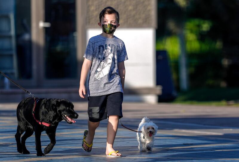 Abu Dhabi, United Arab Emirates, October  23, 2020.    A boy wearing a face mask takes his dogs on a stroll on the Corniche on a Friday morning.
Victor Besa/The National
Section:  NA
for:  Standalone/Weather