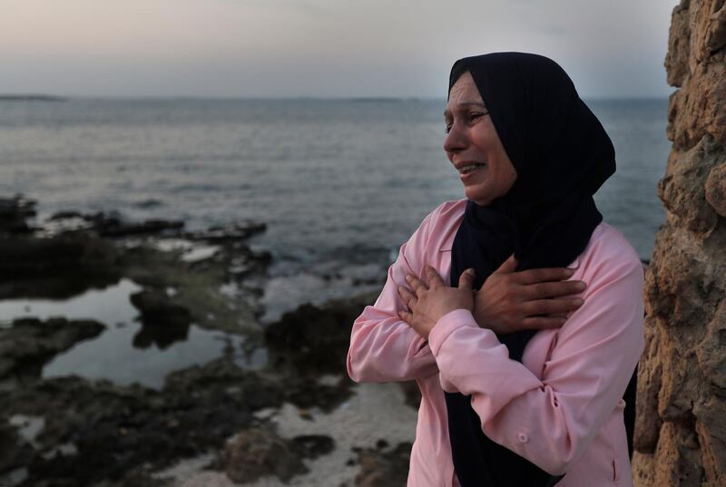 Lebanese Afaf Adulhamid the mother of Mohammed Khaldoun, 27, who is still missing at sea while he was trying with other migrants to reach Cyprus on a boat, cries and prays her son's safe return, as she stands on the coast of Tripoli city, north Lebanon Thursday, Sept. 17, 2020. Mohammed is one of scores of people who have tried in recent weeks to flee Lebanon that is passing through its worst economic and financial crisis in decades to European Union member Cyprus. (AP Photo/Hussein Malla)