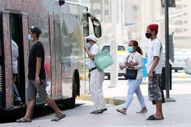 People wearing face masks board a bus in Abu Dhabi. Pawan Singh / The National 