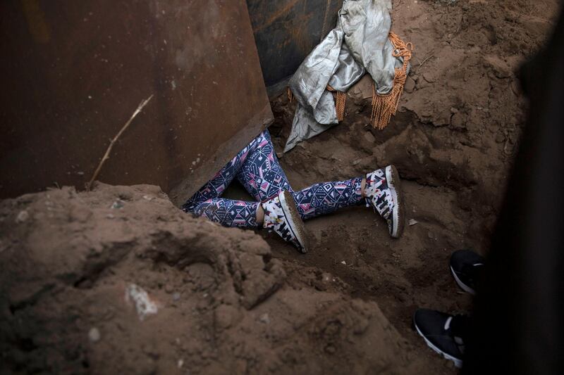 Andrea Nicole Arita, 10, from Honduras, part of a caravan of thousands from Central America, crawls through a hole under a border wall to cross illegally from Mexico to the US in Tijuana. Reuters