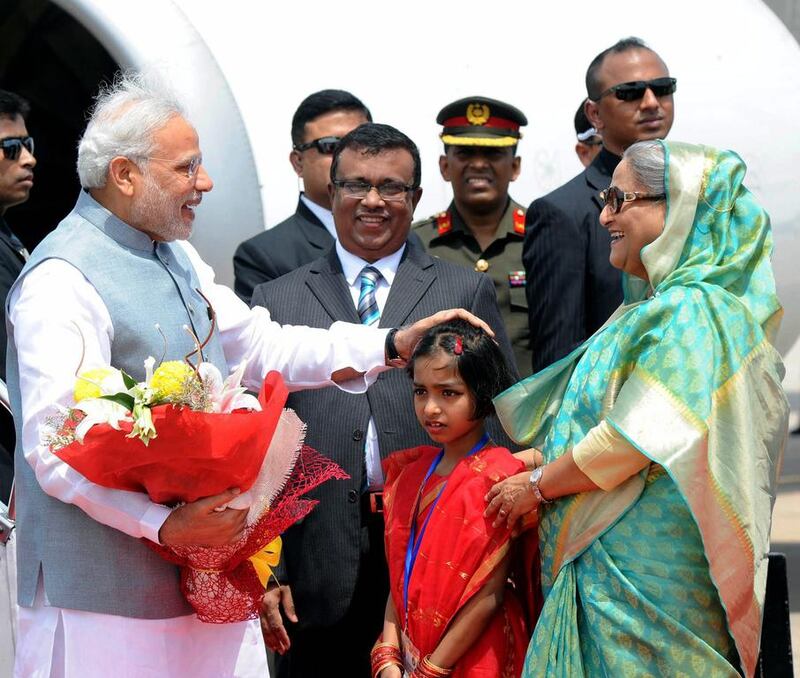 The Indian prime minister Narendra Modi accepts a bouquet from a young girl as he is greeted at the Hazrat Shahjalal International airport in Dhaka by Bangladeshi prime minister Sheikh Hasina at the start of a two-day state visit on June 6, 2015. EPA