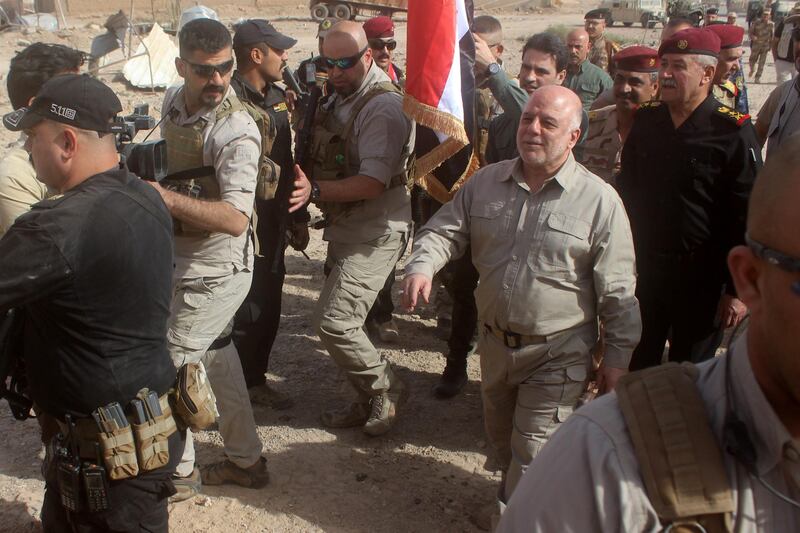 Iraqi Prime Minister Haider al-Abadi prepares to erect a national flag in Al-Qaim on November 5, 2017, after troops retook the border town from Islamic State (IS) group jihadists.
The fall of Al-Qaim leaves IS fighters in Iraq holding just the smaller neighbouring town of Rawa and surrounding pockets of barren desert along the Euphrates river. / AFP PHOTO / MOADH AL-DULAIMI