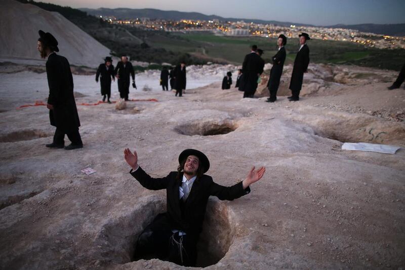 An ultra-Orthodox Jew sits in a hole and prays during a demonstration in Beit Shemesh, Israel, on February 12, 2014. Hundreds protested against the construction of new housing units, believing they would be built at the site of ancient Jewish graves. Abir Sultan / EPA