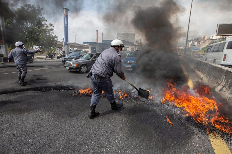 Lebanese policemen try to open a highway blocked by the burning tires during a protest against the collapsing Lebanese pound and the price hikes of goods in Al Zouk area. EPA